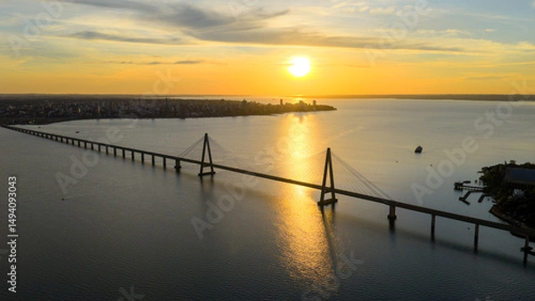 Obraz Breathtaking aerial view of the San Roque González de Santa Cruz Bridge at sunset, with the city of Posadas in the background.