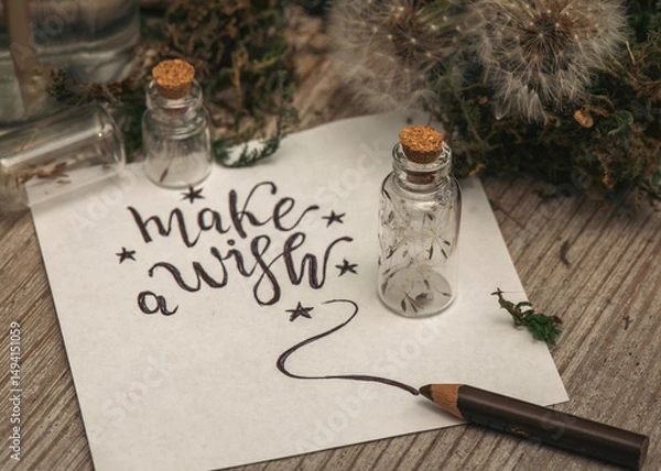 Fototapeta  A close-up of tiny glass jars, each holding a single delicate dandelion parachute. A handmade sign beside them reads “Make a Wish,” adding a sweet, nostalgic touch.