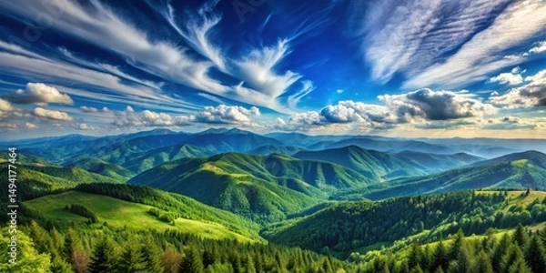 Fototapeta A vast expanse of rugged mountains meets a brilliant blue sky with wispy white clouds, set against a backdrop of rolling hills and lush green forests , scenic view, dramatic sky