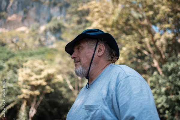Fototapeta Older trekking adventure carries backpacks poles enjoying nature expression looks into the distance observing and possibly guide trekking and trail ecotourism adventure concept.