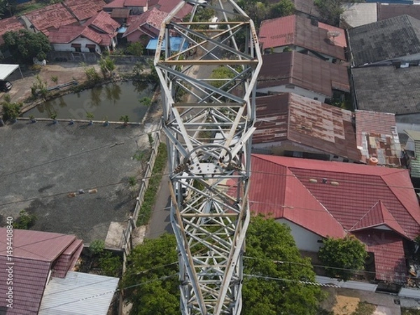 Obraz Electricity generated from generation is distributed through transmission towers before reaching consumers. Transmission towers pass on the roof of densely populated residential house in a city