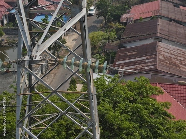 Obraz Electricity generated from generation is distributed through transmission towers before reaching consumers. Transmission towers pass on the roof of densely populated residential house in a city