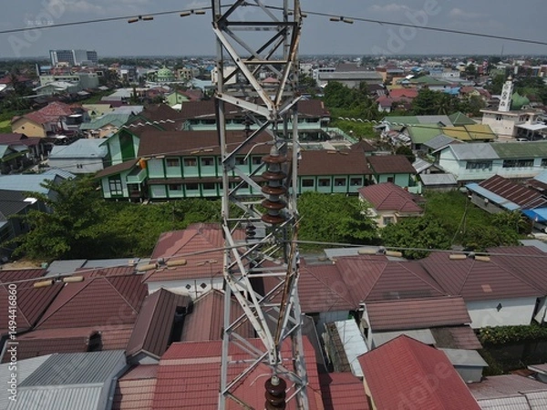 Obraz Electricity generated from generation is distributed through transmission towers before reaching consumers. Transmission towers pass on the roof of densely populated residential house in a city