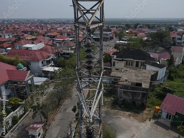 Obraz Electricity generated from generation is distributed through transmission towers before reaching consumers. Transmission towers pass on the roof of densely populated residential house in a city