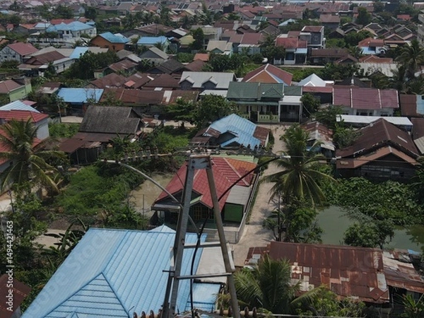 Obraz Electricity generated from generation is distributed through transmission towers before reaching consumers. Transmission towers pass on the roof of densely populated residential house in a city