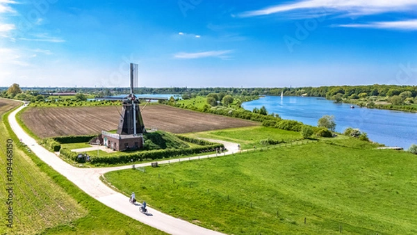 Fototapeta Aerial drone view of typical Dutch countryside landscape with traditional old windmill, fields and river Meuse in spring, the Netherlands
