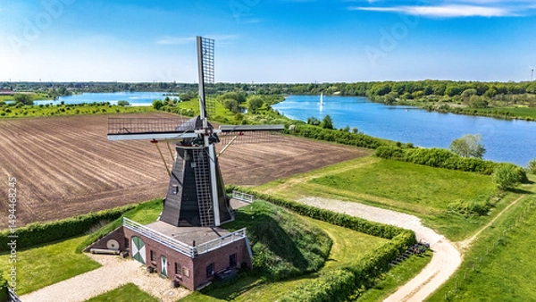 Fototapeta Aerial drone view of typical Dutch countryside landscape with traditional old windmill, fields and river Meuse in spring, the Netherlands