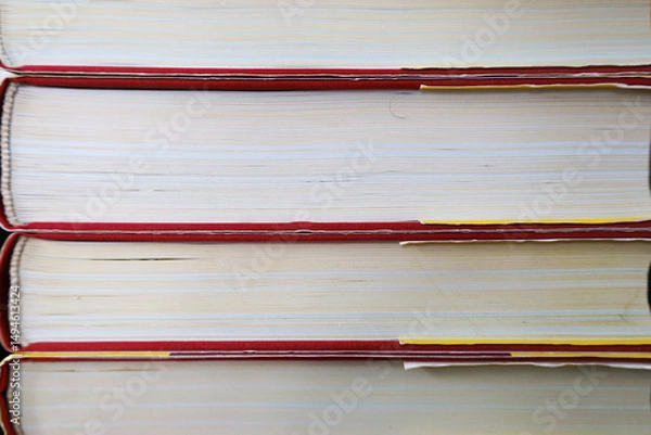 Fototapeta A stack of books with red covers and light pages reveals a multitude of details, symbolizing knowledge and learning. This shot creates an atmosphere of education and reading.