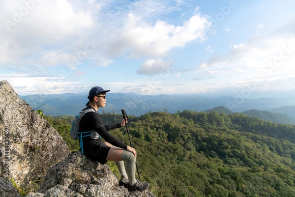 Fototapeta Young man with a backpack enjoying the sunset on the top of the mountain Travel traveler on valley scenery mockup background Mountain climbers watch the sunlight shining on their country journey.