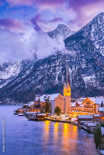 Fototapeta Hallstatt, Austria. Serene Alpine village with snow-covered rooftops on tranquil lake, breathtaking mountain backdrop winter twilight