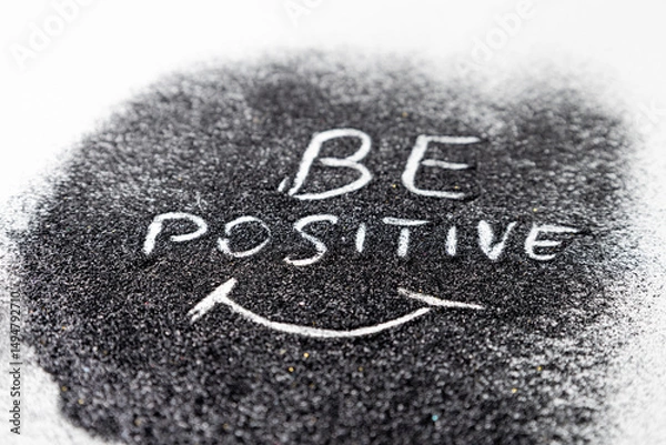 Fototapeta On the black glitters drawing words BE POSITIVE and the smile white background. Abstract minimalist composition from glitter