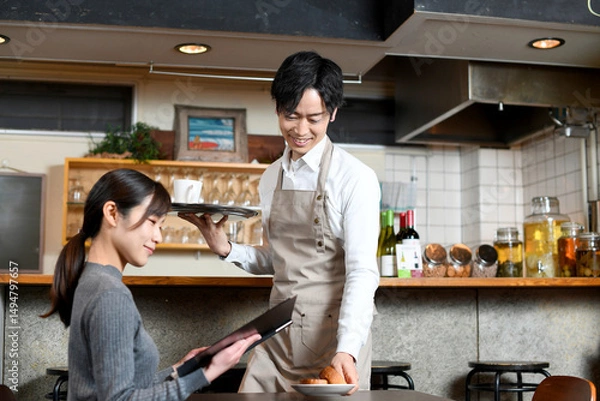 Fototapeta 飲食店で女性客に食事の配膳をする男性店員