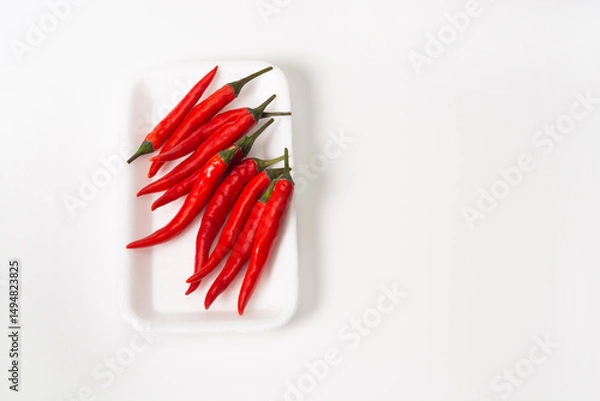 Fototapeta Group of red chili peppers in package on white background. Red chili peppers are packed for sale in the store