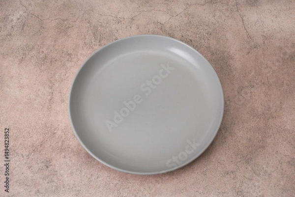 Fototapeta Empty gray ceramic plate with high rim placed on brown background. Flat lay. Top view