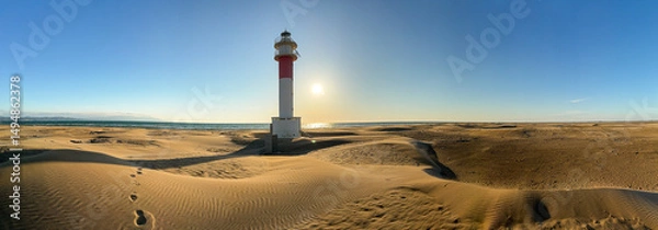 Fototapeta Lighthouse overlooking sandy beach at sunrise.