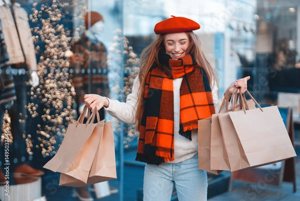 Obraz Woman shopping and enjoying the festive atmosphere while holding multiple bags outside a boutique during the winter season