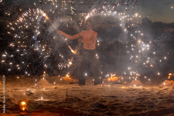 Fototapeta Fire performer lights up the beach, creating beautiful patterns against a sunset backdrop. 