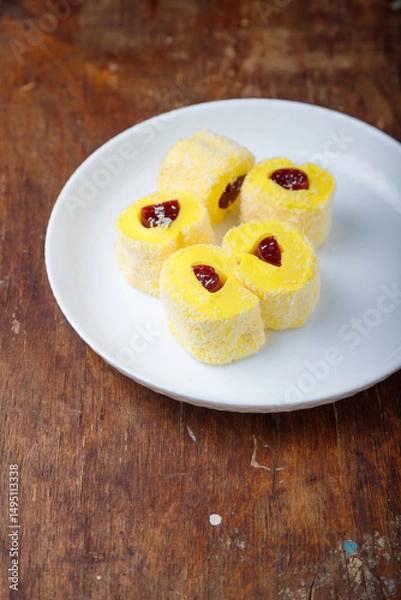 Obraz Turkish delight, yellow locum roll with jelly and coconut flakes on white plate, wooden background. Eastern sweets, oriental food. Traditional tasty dessert. Copy space. Top view