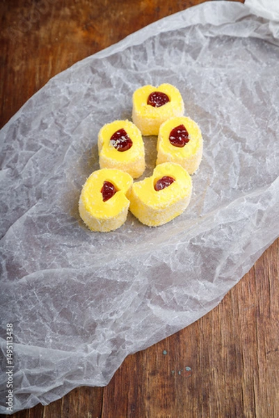 Obraz Turkish delight, yellow locum roll with jelly and coconut flakes on white paper, wooden background. Eastern sweets, oriental food. Traditional tasty dessert. Copy space. Top view