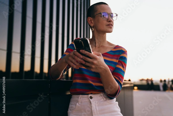Fototapeta Caucasian woman pauses mid-scroll, holding phone and looking away, reflecting on messages or notifications, capturing the intersection of tech focus and real-world awareness