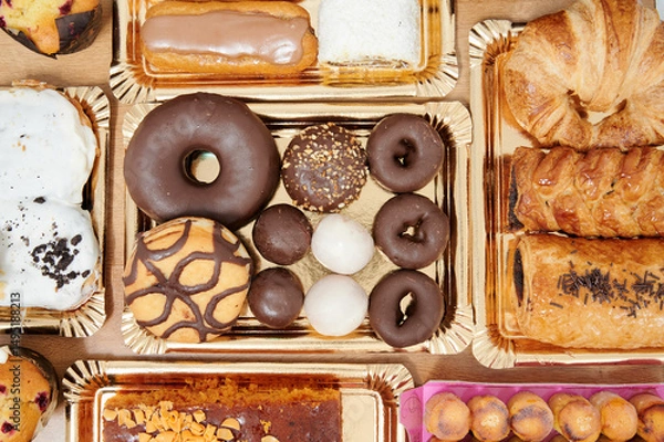 Obraz A tray of assorted pastries including donuts, croissants, and muffins. The donuts are chocolate and white, and the croissants are golden brown