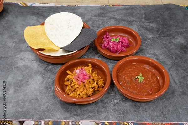 Obraz A plate of food with a bowl of meat and a bowl of sauce. There are also some tortilla chips on the plate