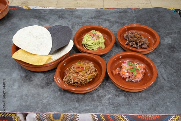 Fototapeta A plate of food with five different dishes on it. The dishes are in small bowls and the plate is on a table