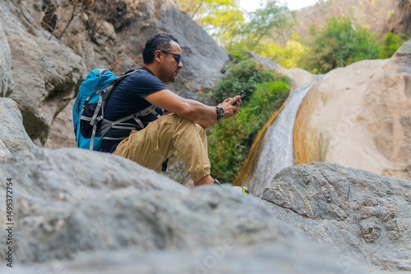 Obraz Hiker using smartphone near waterfall in puebla, mexico