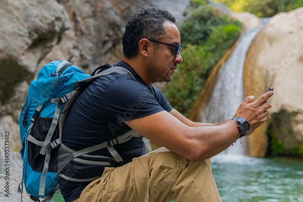 Obraz Tourist using smartphone near waterfall in puebla, mexico