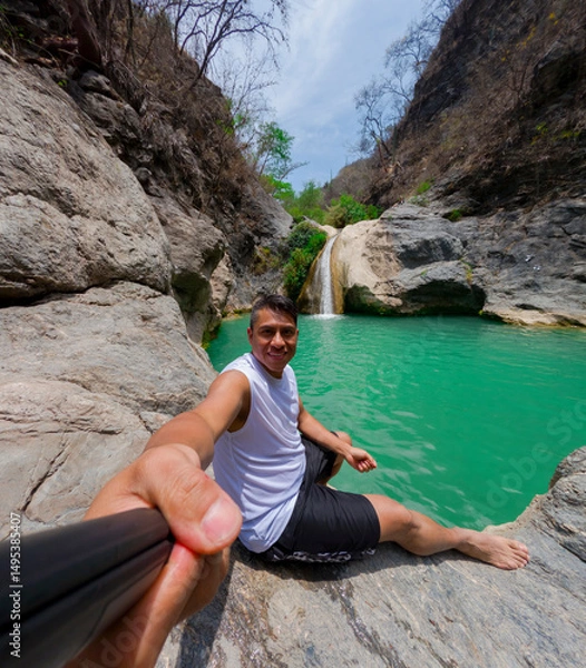 Obraz Young man taking a selfie near a waterfall in a rocky canyon