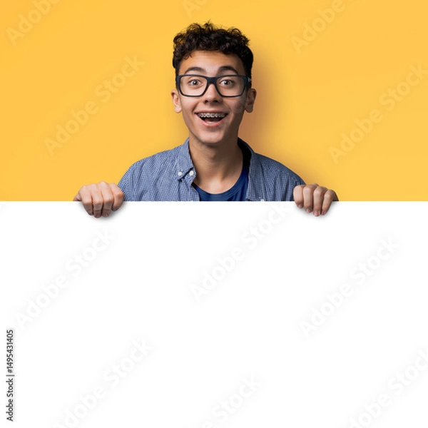 Fototapeta Image of happy man wear glasses, braces stand behind blank empty banner mockup sign board signboard, advertise show pointing area for slogan text isolate yellow background. Dental care ad