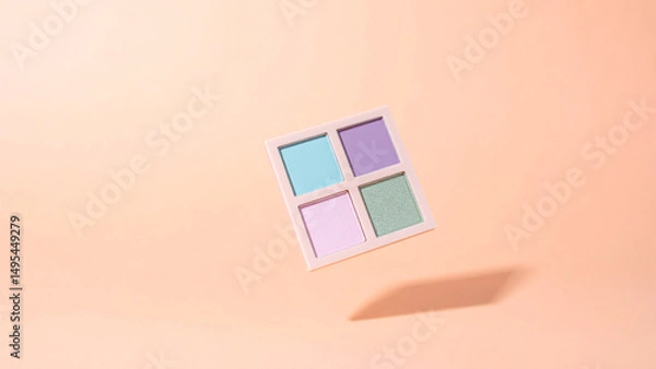 Fototapeta Pastel eyeshadow palette with four soft tones floating above peach background under studio lighting
