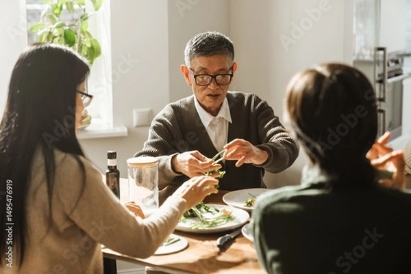 Fototapeta Grandfather and grandmother sitting at a table holding greens while their grandson sits next to them