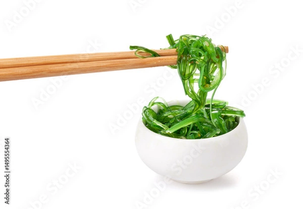 Fototapeta Chopsticks holding Japanese seaweed salad. Japanese cuisine - Wakame salad, Chuka seaweed salad isolated on a white background.