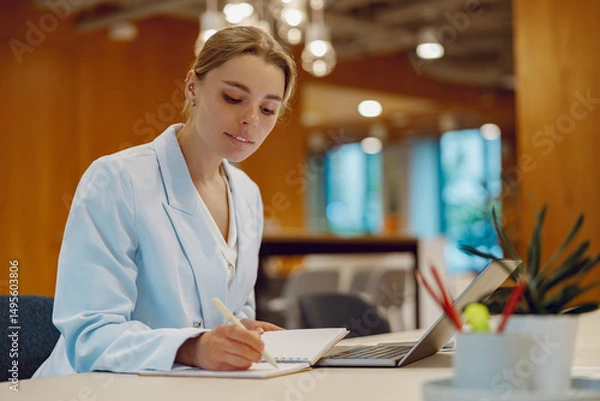 Obraz In a chic and stylish office setting, a dedicated healthcare professional diligently writes notes with focus