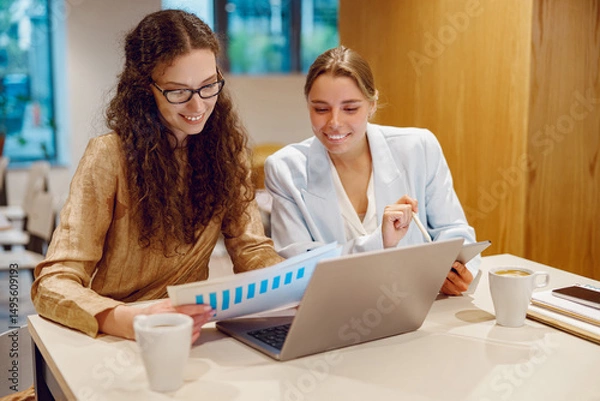 Obraz Two dedicated professionals engage in a highly productive meeting, equipped with laptops and detailed reports