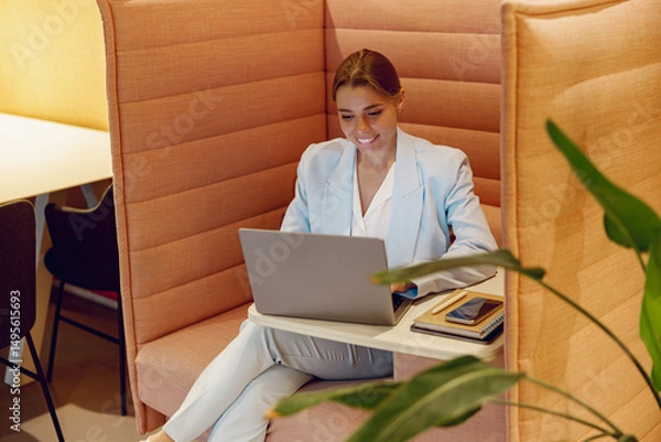 Obraz An ambitious and focused professional woman diligently working on her laptop in a stylish and chic office nook
