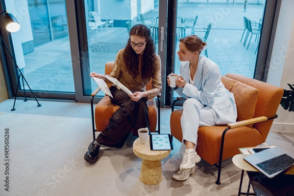 Obraz Two women were actively engaged in a vibrant and creative discussion within a stylish office environment