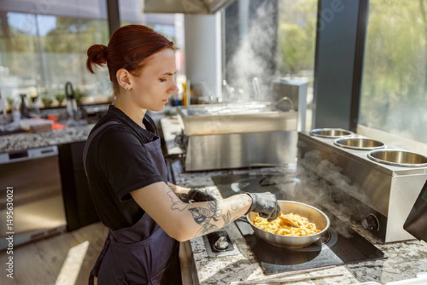 Obraz A skilled chef focuses on preparing pasta in a modern kitchen filled with steam and fresh ingredient aromas