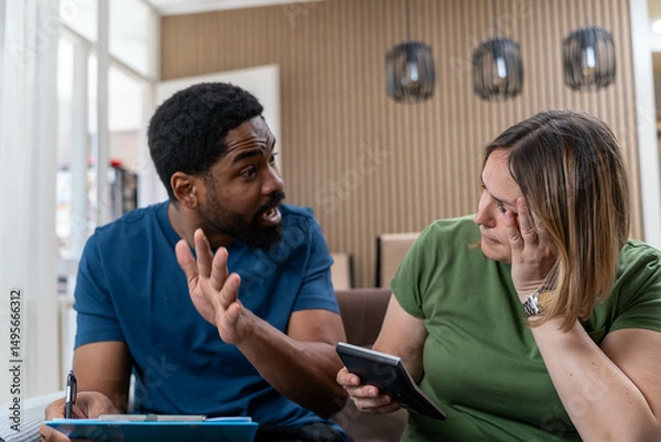 Fototapeta Couple analyzing family bills. Desperate couple doing their accounts sitting on the sofa. Couple managing the debt. Sad interracial couple, finance debt and anxiety in financial planning, mortgage