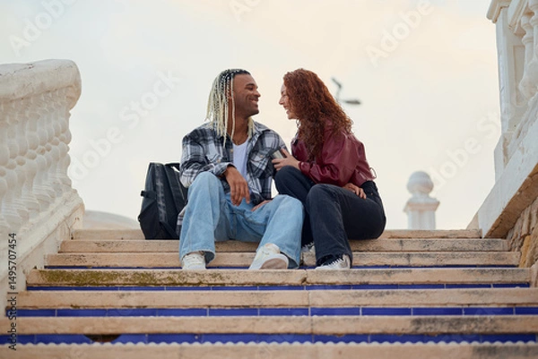 Fototapeta Couple enjoying a joyful moment on outdoor steps at dusk