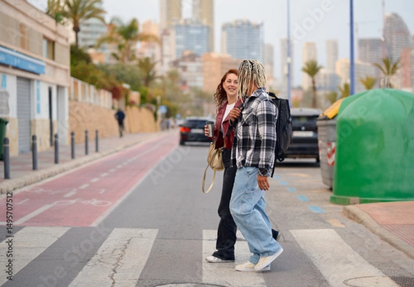 Fototapeta Friends enjoying a casual stroll on a city street during the evening