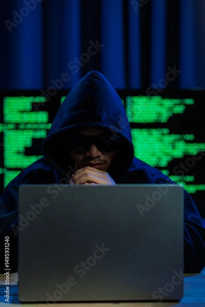 Obraz Male hacker in a dark room trying to steal global user data to sell on the dark web, representing serious threats in modern cybercrime.