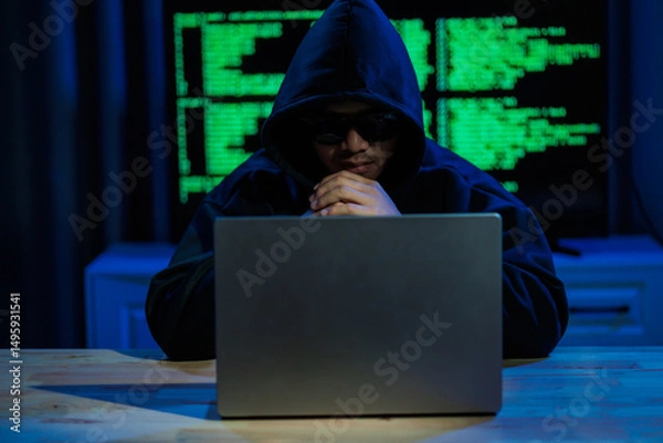 Fototapeta Male hacker in a dark room trying to steal global user data to sell on the dark web, representing serious threats in modern cybercrime.