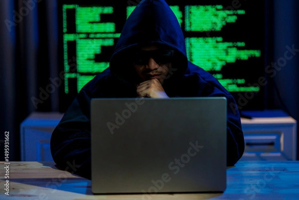 Fototapeta Male hacker in a dark room trying to steal global user data to sell on the dark web, representing serious threats in modern cybercrime.
