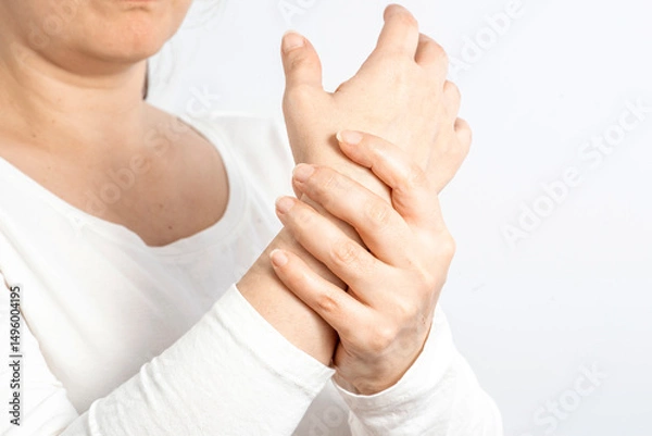 Fototapeta Arthritis symptoms, suffering from pain. The hands of the woman massage a painful wrist. Inflamed male joint, stiffness of movement. Close up view