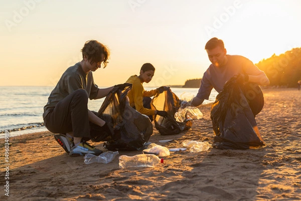 Fototapeta Earth day. Volunteers activists team collects garbage cleaning of beach coastal zone. Woman mans puts plastic trash in garbage bag on ocean shore. Environmental conservation coastal zone cleaning