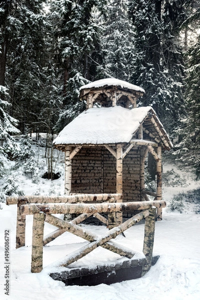 Fototapeta Winter landscape. Gazebo and the bridge leading to it across the ravine made of birch logs in the city park.