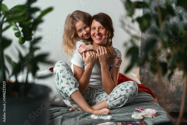 Fototapeta Daughter hugging her mother from behind with smile, cozy indoor scene of affection and bonding. Concept of close family connection, gentle parenting, and emotional warmth in home. Family happy 