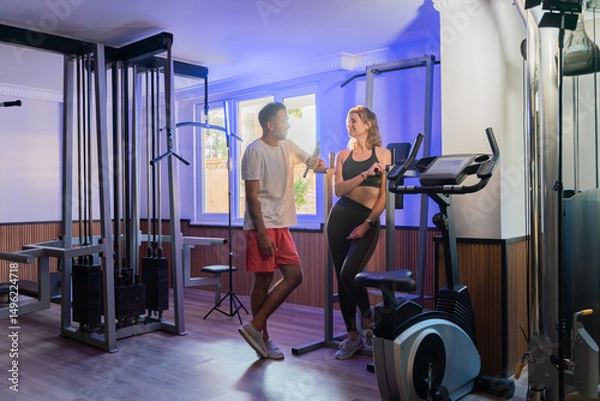Fototapeta Couple working out in home gym, Personal trainer assisting client